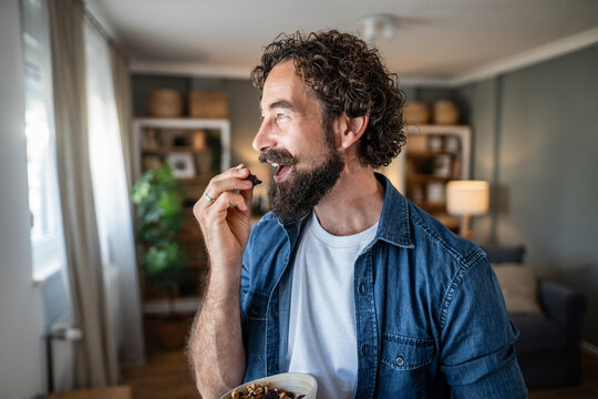 Man enjoying healthy dried fruit and nut snack at home