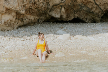 Portrait of a young girl in a yellow swimsuit on the beach.