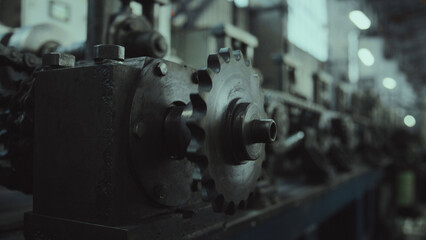 Heavy duty industrial machine detail featuring a metal sprocket wheel and chain on a production line, showing mechanical engineering and robust manufacturing equipment in a factory setting