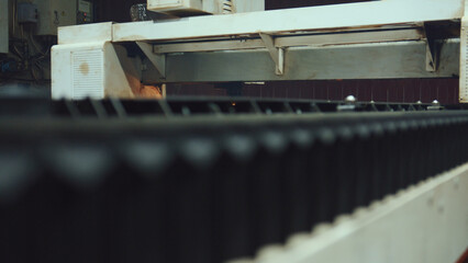 Industrial laser cutter automatically working on a metal sheet, producing custom shapes and...