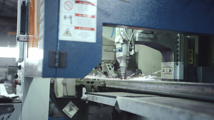 Laser cutting machine performing precision cutting on a metal workpiece, creating bright sparks in an industrial manufacturing environment, demonstrating advanced technology and automation