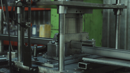 Heavy industrial machine performing precise metal shaping work on a metal profile, embodying modern manufacturing and production efficiency in a workshop environment