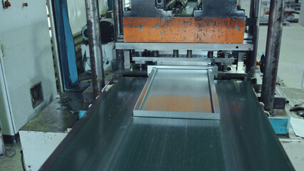 Metal forming machine in operation, processing a raw aluminum sheet into a finished industrial frame, showcasing manufacturing automation and precision in a modern factory setting