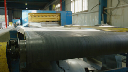 Close up of a moving black rubber conveyor belt transporting metal sheets along a production line...