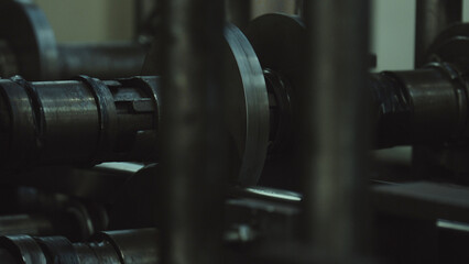 Industrial metal rollers shaping a continuous steel sheet on a factory production line, close up of...