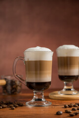 Layered coffee latte drinks. Hot coffee drinks in glass mugs, brown background