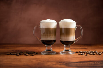 Layered coffee latte drinks. Hot coffee drinks in glass mugs, brown background