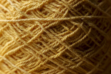 Warm yellow yarn ball close up showing detail wool thread texture. cozy abstract background of...