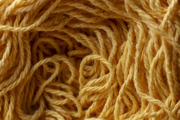Close up of tangled yellow yarn creating natural texture background. string fiber and material show intricate details, evoking feeling of warmth and comfort
