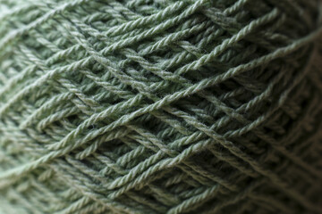 Cozy close up of green ball of wool yarn. texture of natural fiber thread makes crisscross pattern, perfect for crafting, knitting, or crocheting projects