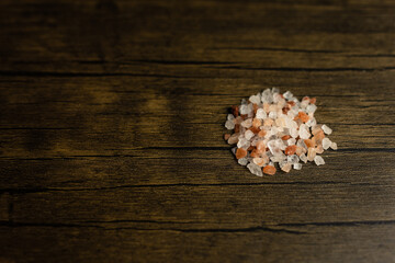 close-up of pink Himalayan salt against a dark wooden background in a horizontal orientation with copy space available