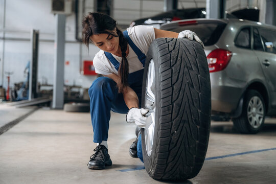 Seasonal replacement conception. Woman mechanic is with tire in the modern car workshop