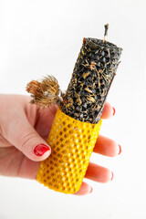 Hand holding a candle made of beeswax and herbs with a colorful textured base