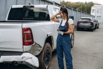 This is bad, shocked, standing. Woman mechanic is checking the damaged pickup truck car outdoors © standret