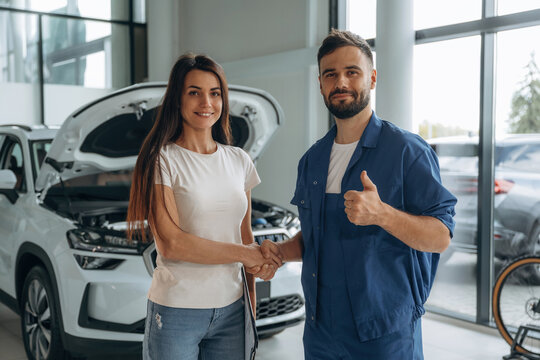 Deal, doing handshake. Woman customer is in the car repair service station with mechanic