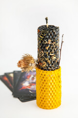 Black and yellow ritual candle with herbs on Tarot cards for luck and protection