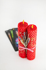 Decorative red candles with dried flowers and tarot cards displayed on a white background
