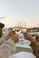 Three female friends raising glasses in a cozy celebration under the evening sky. Warm and cheerful atmosphere, perfect for lifestyle, friendship, and social gathering concepts.