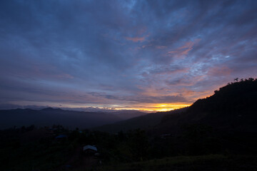 Vibrant sunrise paints mountain landscape. Dramatic sky showcases colorful cloud formation over horizon. Tranquil nature outdoors creates serene silhouette at dawn, evoking peaceful wonder