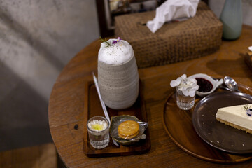 Delightful arrangement of sweet treats and refreshing beverages awaits warm wooden table. Creamy drinks and delicious slice of cake create an inviting atmosphere for relaxation and pure enjoyment