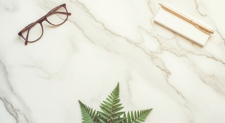 Eyeglasses a pen on a pad and green fern leaves are arranged on a white marble surface