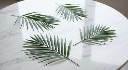 Four green leaves resembling palm fronds are scattered on a white marble table with gray veining and soft shadows