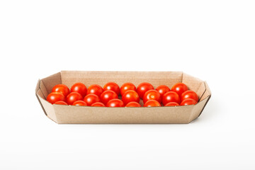 Fresh red cherry tomatoes in a cardboard box on a white background. Isolated. Front view