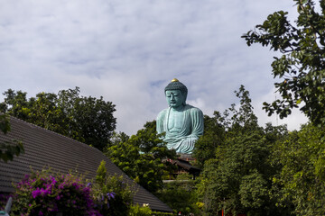 Giant Buddha statue, serene and peaceful monument, rises majestically above an Asian temple green...
