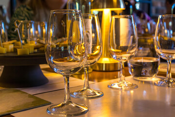 Elegant wine glasses on a festive table with cheese snacks and warm golden light