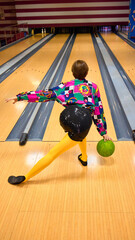 Woman in colorful patterned shirt and yellow tights bowling with green ball. Concept of playful retro revival, eclectic fashion culture, vintage lifestyle imagery, and striking editorial design.