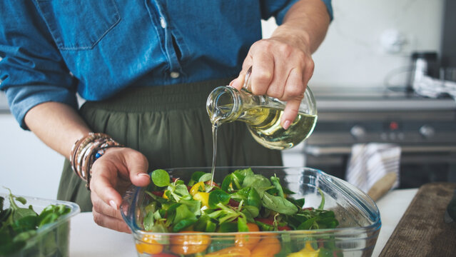 Woman Adding Olive Oil In Vegetable Salad