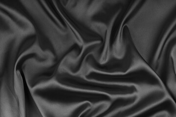 Crumpled, wrinkled black colored glossy silk satin texture. Shiny smooth fabric with soft folds, cloth with wave drapery. Elegant and rich background, wallpaper, backdrop. Flat lay, top view