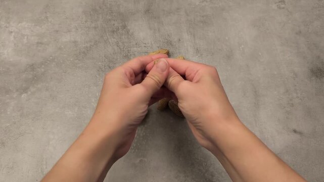 Hands skillfully shelling peanuts in a continuous motion sequence, showcasing the intricate process of removing shells from the nuts on a textured surface