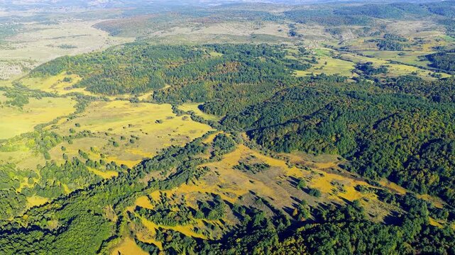 Drone aerial moving forward over Glasinačko polje plateau fields and forests on Romanija mountain Bosnia