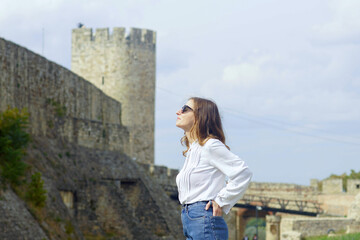 A walk in the Belgrade Fortress: a smiling woman stands with the Despot Stefan Tower in the...