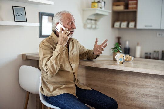 Happy senior man talking on smartphone with family friends. Older mature grandfather with cell phone talking with grown up children, resting at home. Older generation modern tech usage.