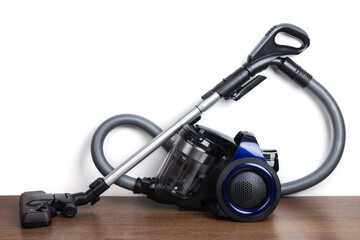 Modern vacuum cleaner near white wall in room