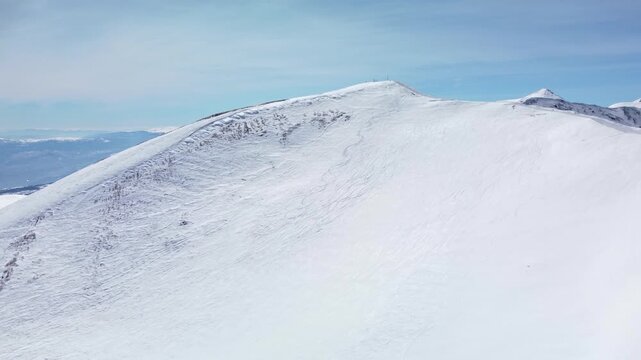 Aerial view of a mountain slope used for freeride skiing. Visible snowcat tracks on the egde and summit. Ski and snowboard tracks on the powder snow.