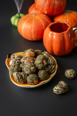 Autumn composition with tied Chinese tea, cups of tea, and pumpkins on a dark background in the style of Halloween