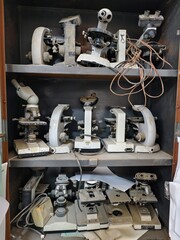 Basrah, Iraq - October 1, 2025: Dusty, unused microscopes stored on shelves in a university lab.


