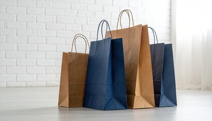 Four shopping bags, different colors, stand against a white brick wall