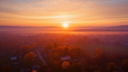 Fototapeta premium Sunrise over town bringing warmth to a foggy valley