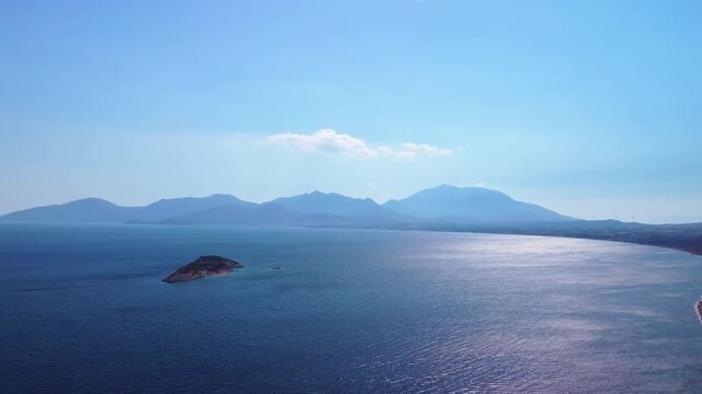 aerial footage capturing the stunning coastal landscape and shimmering Aegean Sea on the journey towards the historic Knidos Ancient City in Turkey. Featuring a picturesque small island, distant mount