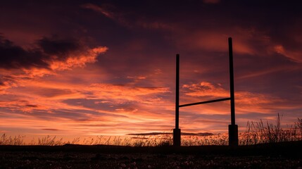 Dramatic Sunset Silhouettes Rugby Goalposts Against Fiery Crimson and Orange Sky.