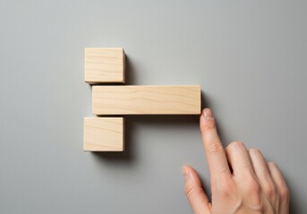 Hand Arranging Wooden Blocks on Gray Background