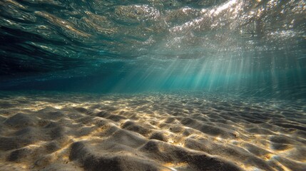 Underwater sunbeams illuminate sandy seabed