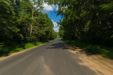 Obraz premium The effect of speed on the road and blurred objects. View of the road on a sunny summer day.