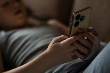 A child with an arm in a cast uses a phone