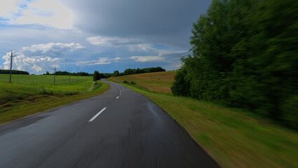 Naklejka premium The effect of speed on the road and blurred objects. View of the road on a sunny summer day.