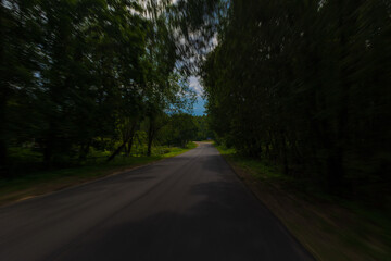 Obraz premium The effect of speed on the road and blurred objects. View of the road on a sunny summer day.
